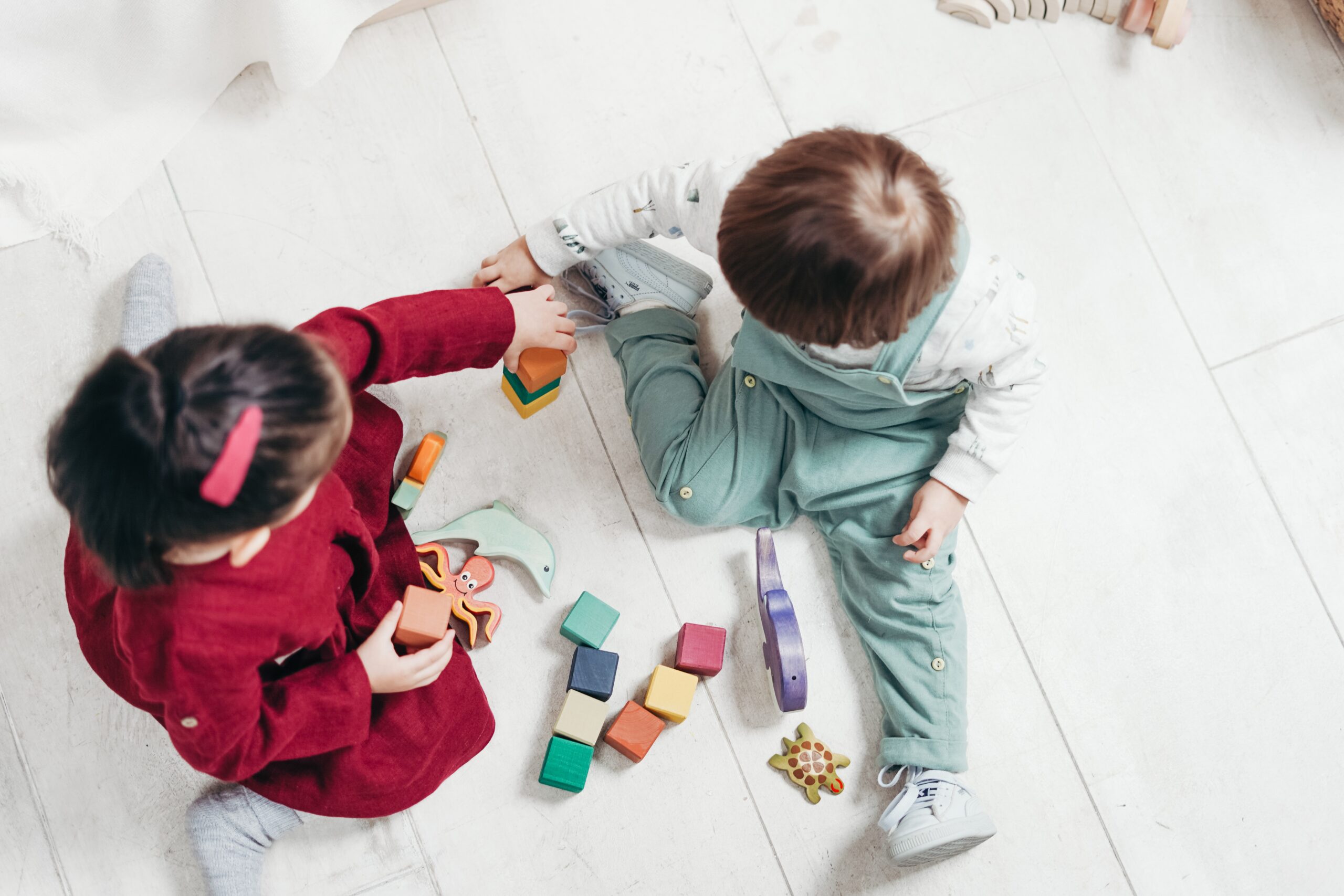 Two young children playing with colourful wooden blocks