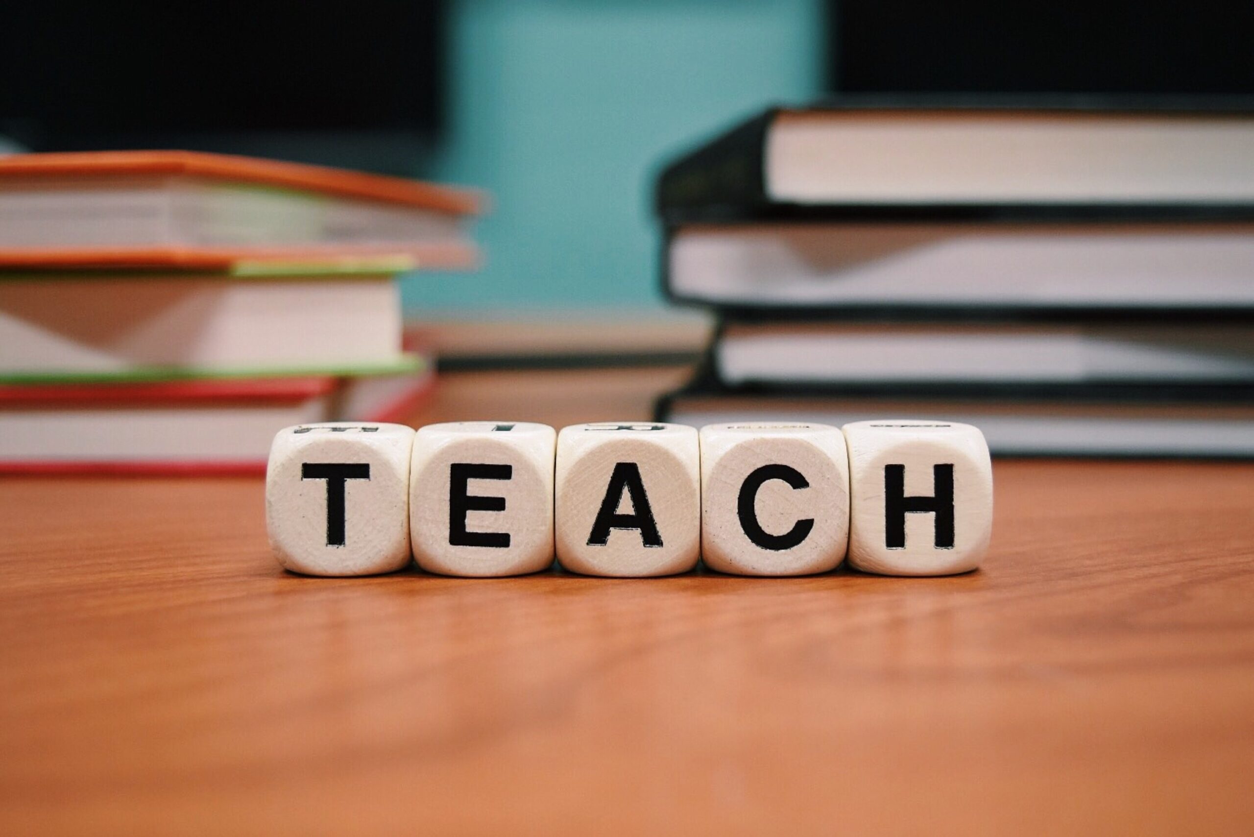 Letter dice arranged on a desk to spell out the word teach